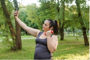 Woman with weight in the park taking selfie